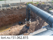 Large diameter plastic pipe for water supply. A smooth black plastic pipe with a blue stripe is placed in the trench. Installation of water supply systems. The excavation where the pipes are connected. Стоковое фото, фотограф Эдуард Белкин / Фотобанк Лори