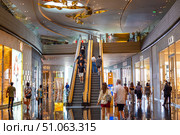 Shoppers use escalators and walk past designer stores such as Gucci, Dior and Celine at the upscale Iconsiam shopping mall with reflective floors. Thailand, Bangkok (2024 год). Редакционное фото, фотограф Коханова Наталья / Фотобанк Лори