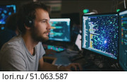 Coder works on complex programming tasks at a tech workspace during evening hours with multiple screens showing data analysis. Стоковое AI-видео, аниматор Сергей Толмачёв / Фотобанк Лори