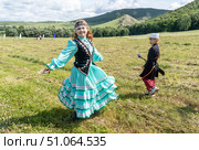 Девочка в башкирском костюме кружится в танце на фоне холмов и леса, а за ней наблюдает мальчик с луком. Редакционное фото, фотограф Андреева Тамара Викторовна / Фотобанк Лори
