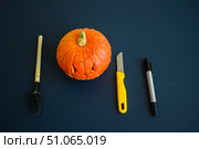 Little pumpkin with spiteful grimass, paper knife, pen, trowel over black background. Halloween concept, flat lay, top view. The process of making jack-o-lantern. flat lay. Стоковое фото, фотограф Михаил Решетников / Фотобанк Лори
