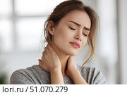 Красивая молодая девушка, держащаяся руками за шею от боли, стоит в ярком современном интерьере. Стоковое AI-изображение, AI-художник Максим Коломыченко / Фотобанк Лори