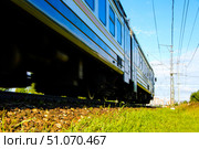 A train is traveling down the tracks with a green grassy area in the background. Russia. Moscow oblast. 14.08. 2025. Редакционное фото, фотограф Ярославский Максим / Фотобанк Лори