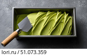Metal spatula scooping pistachio or matcha ice cream from a container. Стоковое AI-изображение, AI-художник Юрий Поздников / Фотобанк Лори