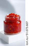 Glass jar brimming with vibrant red hot sauce on white block. Стоковое AI-изображение, AI-художник Юрий Поздников / Фотобанк Лори