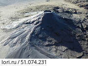 A mud volcano and a stream of grey clay from an eruption and gas escape. Cracked soil surface. Texture of a mudflow. Стоковое фото, фотограф Наталия Кирсанова / Фотобанк Лори