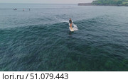 November 26, 2024. Bali, Indonesia. Surfer woman rides on surfboard in blue ocean with crashing ocean wave. Редакционное видео, видеограф Wonderful nature / Фотобанк Лори