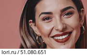 Close-up portrait of a smiling young woman with facial piercings—gold nose ring and lip (labret) piercing, bold brows and red lipstick, perfect teeth (4K, 16:9) Стоковое AI-видео, аниматор Владислав Войтов / Фотобанк Лори