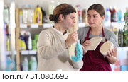Friendly female sales consultant presenting various body sponges to customer in personal care products store. Focused man carefully reading labels, evaluating features, comparing textures and shapes. Стоковое видео, видеограф Яков Филимонов / Фотобанк Лори