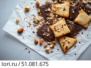 An array of ornate cookies rests casually on crinkled parchment. Adorned with chocolate, nuts, and seeds, these artisanal treats illustrate culinary creativity in a laid-back style. Стоковое AI-изображение, AI-художник Nart / Фотобанк Лори