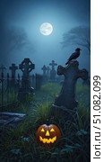 A spooky graveyard scene at night with a full moon. A carved pumpkin sits on the ground, and a crow perches on a gravestone. Fog envelops the area. Стоковое AI-изображение, AI-художник Nart / Фотобанк Лори