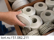 Customer selecting white plastic trim rings for stretch ceiling installation in a hardware store, used to secure and finish recessed lighting openings. Стоковое фото, фотограф Татьяна Терехина / Фотобанк Лори