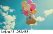A bag with a dollar sign is lifted by colorful balloons against a bright blue sky with fluffy clouds. The scene conveys a sense of joy and financial success. Стоковое AI-видео, аниматор Nart / Фотобанк Лори