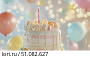 A colorful birthday cake with a single candle on top. The cake is decorated with pastel-colored frosting and surrounded by balloons in various colors. Стоковое AI-видео, аниматор Nart / Фотобанк Лори