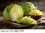 Organic freshly white cabbage on rustic table surface. Green fresh cabbage. Partially sliced raw shredded cabbage and a half on a wooden cutting board with a knife. Preparation of vegetables salad. Стоковое AI-изображение, AI-художник Марина Демидюк / Фотобанк Лори