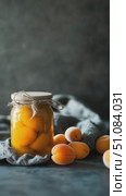 A jar of preserved apricots sits on a gray cloth. Fresh apricots are scattered around the jar. The scene highlights food preservation and healthy eating. Стоковое AI-видео, аниматор Nart / Фотобанк Лори