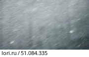 Abstract close-up of falling snowflakes creating a blurred winter background. Soft white snow covers the ground, evoking a cold and serene atmosphere. Стоковое AI-видео, аниматор Nart / Фотобанк Лори