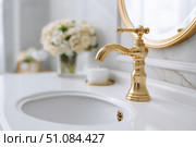 Modern golden faucet and marble stone sink. Stylish white sink, faucets in a light interior. Copper brass tap. Domestic Appliances. Clean bright bathroom. Household equipment. New Contemporary style. Стоковое AI-изображение, AI-художник Марина Демидюк / Фотобанк Лори