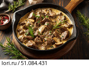 Meat and mushrooms. Dish of stir-fried beef fillet and mushrooms in a creamy thick sauce, served on an iron plate on a wooden board, close-up view. Gourmet food. Beef stroganoff large pieces. Stir Fry. Стоковое AI-изображение, AI-художник Марина Демидюк / Фотобанк Лори