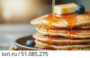 Stack of fluffy pancakes topped with butter and drizzled with syrup, garnished with fresh blueberries. A delicious breakfast scene. Стоковое AI-видео, аниматор Nart / Фотобанк Лори