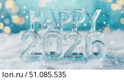 Ice letters spell out 'Happy 2026' on a snowy surface. The background features a soft blue hue with bokeh lights, creating a festive atmosphere. Стоковое AI-видео, аниматор Nart / Фотобанк Лори