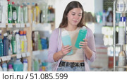 Happy young girl choosing shampoo or shower gel in cosmetics store. Стоковое видео, видеограф Яков Филимонов / Фотобанк Лори