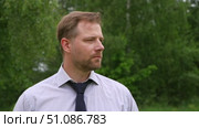 Confident Businessman in Natural Setting. Man stands in front of lush green backdrop. Remote working. Portrait of happy mid adult male wearing formal clothes, shirt and tie, glasses. Find inspiration. Стоковое видео, видеограф Марина Демидюк / Фотобанк Лори