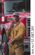 Firefighter in uniform stands proudly in front of a fire engine during a training drill at the station. Стоковое AI-видео, аниматор Сергей Толмачёв / Фотобанк Лори