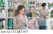 Girl view trademark sign on label, pick eco friendly liquid detergent, man shopping in background. Стоковое видео, видеограф Яков Филимонов / Фотобанк Лори