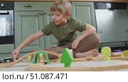 Cute little blonde child boy sitting on the floor playing with wooden toy train. Toddler kid plays railway. Made of natural materials. Birthday gift. Preschool employment. Brain, coordination exercise. Стоковое видео, видеограф Марина Демидюк / Фотобанк Лори