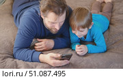 Father and son little boy laughing and using phone. They watching funny videos together, playing games on smartphone. Concept technology, smartphone addicted. Fun weekend activity. Modern fatherhood. Стоковое видео, видеограф Марина Демидюк / Фотобанк Лори