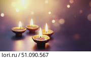 Four glowing diya lamps on a surface, symbolizing the Diwali festival. The lamps emit warm light, surrounded by a soft bokeh effect, creating a festive atmosphere. Стоковое AI-видео, аниматор Nart / Фотобанк Лори
