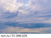 Mysterious clouds drift across a light blue sky at dusk revealing hints of sunlight and fantastic formations. Стоковое фото, фотограф Владимир Разгуляев / Фотобанк Лори