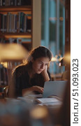 Young woman studying in a cozy library during the evening, focused on her laptop. Стоковое AI-видео, аниматор Сергей Толмачёв / Фотобанк Лори
