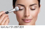 Woman applying makeup with brush for a flawless look in a beauty routine. Стоковое AI-изображение, AI-художник Katsiaryna Repich / Фотобанк Лори