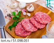 Raw hamburger patties on wooden board with condiments. Стоковое фото, фотограф Яков Филимонов / Фотобанк Лори