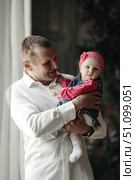 Holding His Little One Papa Gazes Lovingly at His Daughter Indoors. Стоковое фото, фотограф Aleksandr Golubev / Фотобанк Лори