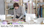 Female dressmaker draws sketch of future clothing on paper using patterns in a sewing workshop. Стоковое видео, видеограф Яков Филимонов / Фотобанк Лори