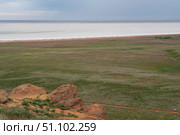 Fancy stones on the slopes of Bolshoe Bogdo Mountain and the salt lake Baskunchak in the distance on a summer day, Bogdinsko-Baskunchak Nature Reserve, Akhtubinsky district, Astrakhan region, Russia. Стоковое фото, фотограф Ula Ulachka / Фотобанк Лори