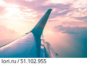 Airplane wing soaring through a beautiful pink and orange sunset sky, offering a breathtaking view of the clouds and landscape below, creating a captivating travel image. Стоковое фото, фотограф Ольга Ильина / Фотобанк Лори