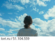 Woman looking up at cloudy sky contemplating the immensity of nature. Стоковое AI-изображение, AI-художник Иван Рябоконь / Фотобанк Лори