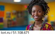 Portrait of vibrant, smiling Black woman with dreadlocks and colorful attire in bright, inviting classroom setting. Стоковое AI-изображение, AI-художник Данила Большаков / Фотобанк Лори