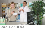 Attentive young girl controlling QR code of medicament and apothecary giving offer in drugstore. Стоковое видео, видеограф Яков Филимонов / Фотобанк Лори