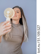Young woman staying cool and happy with her personal portable fan on a warm sunny day outdoors. Стоковое фото, фотограф Svetlana Golovco / Фотобанк Лори