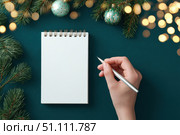Woman's hand writing in empty notebook at the desk with Christmas decoration. Back to life, goal list. Plan, goals, checklist, idea concept. Top view, copy space. New Year. Blank White Paper Sheet. Стоковое AI-изображение, AI-художник Марина Демидюк / Фотобанк Лори