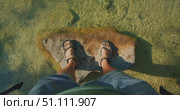 Male feet in sandals stand on river rock by shallow transparent river stream. Стоковое видео, видеограф Ольга Сухарева / Фотобанк Лори