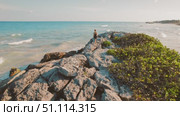 Aerial view of woman walking on rocky shore and looking at ocean in Tulum Yucatan. Стоковое видео, видеограф Ольга Сухарева / Фотобанк Лори
