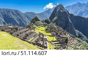 Beautiful panoramic view of Machu Picchu. Dilapidated stone buildings, terraces, green grass. Huayna Picchu and a mountain range against a blue sky and clouds. Peru. Cusco. Lost City of the Incas. Стоковое фото, фотограф Вера Ивановна Кубарева / Фотобанк Лори