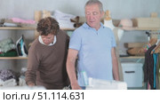 Male tailor stands near a mature client and uses a measuring tape to take measurements to make clothes in the workshop. Стоковое видео, видеограф Яков Филимонов / Фотобанк Лори