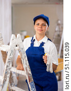 Portrait of contented young female builder in blue overalls during the repair of cottage. Стоковое фото, фотограф Яков Филимонов / Фотобанк Лори